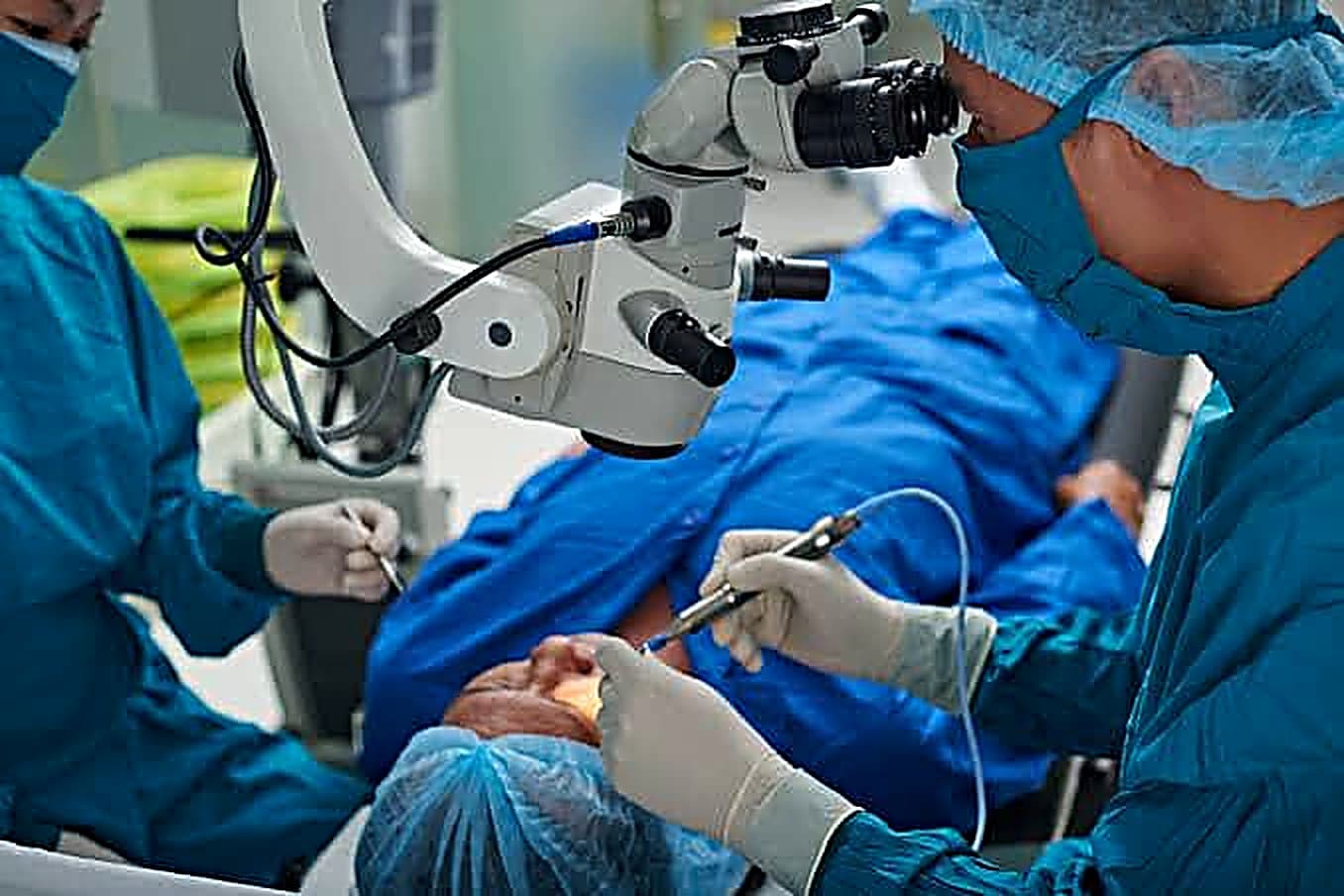 Eye surgeons performing a procedure under an operating microscope in the theatre